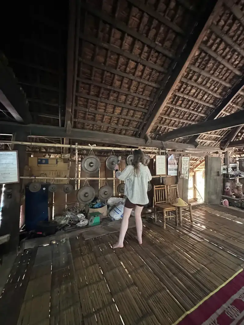 People seen from behind near large gongs outside a wooden building