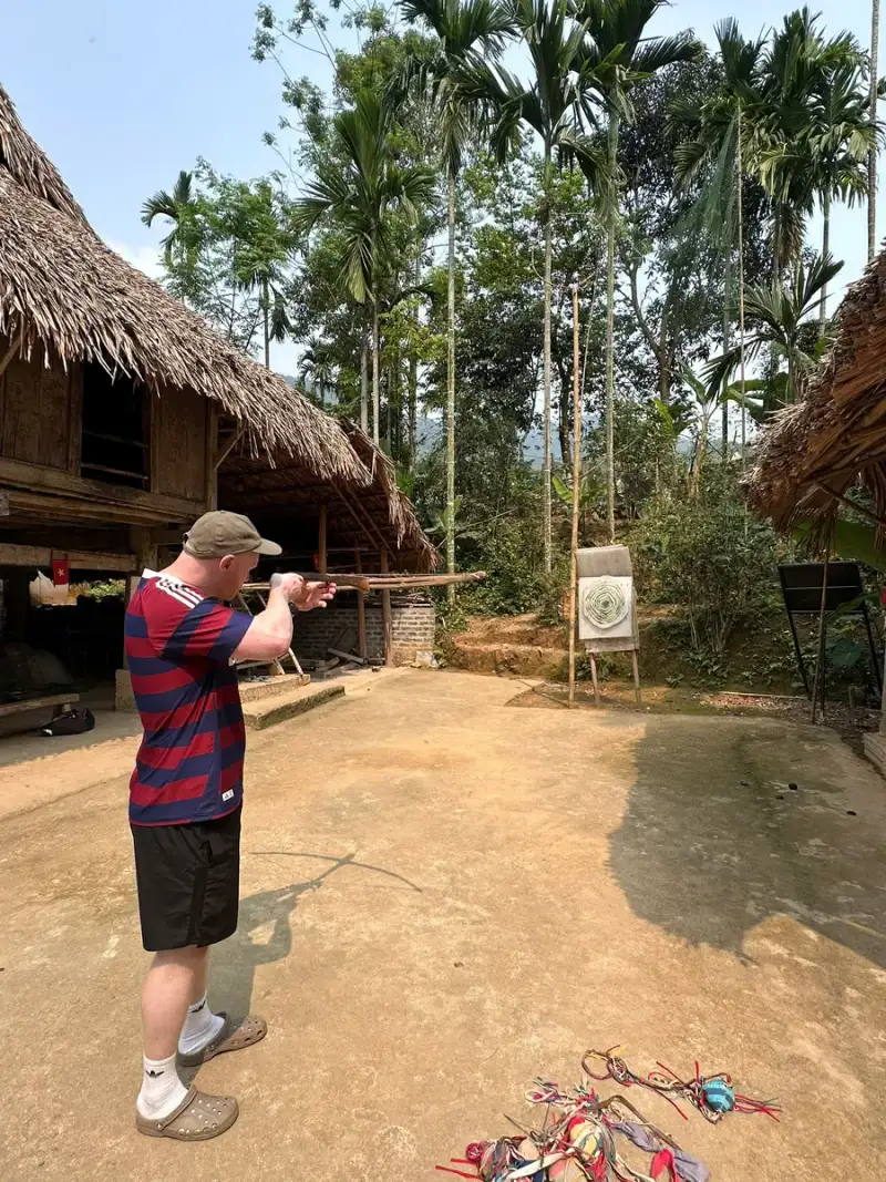 People seen from behind in a courtyard with wooden buildings